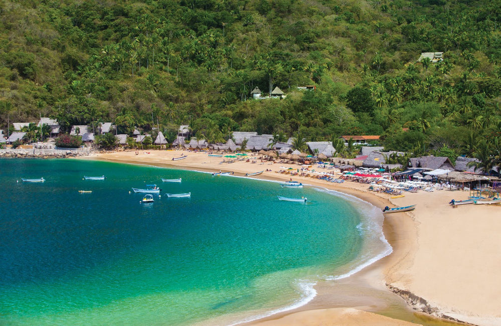 Boats moored beside Yelapa’s beach and jungle-covered hills in Mexico.