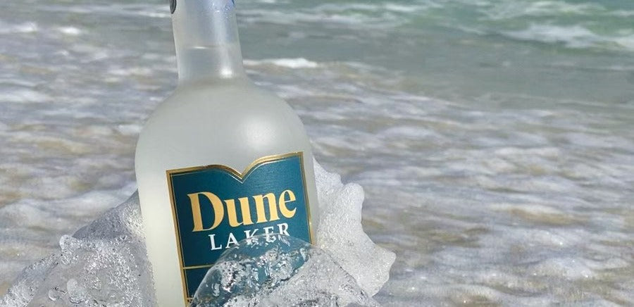 A bottle of Dune Laker vodka standing in the surf on a Florida panhandle beach