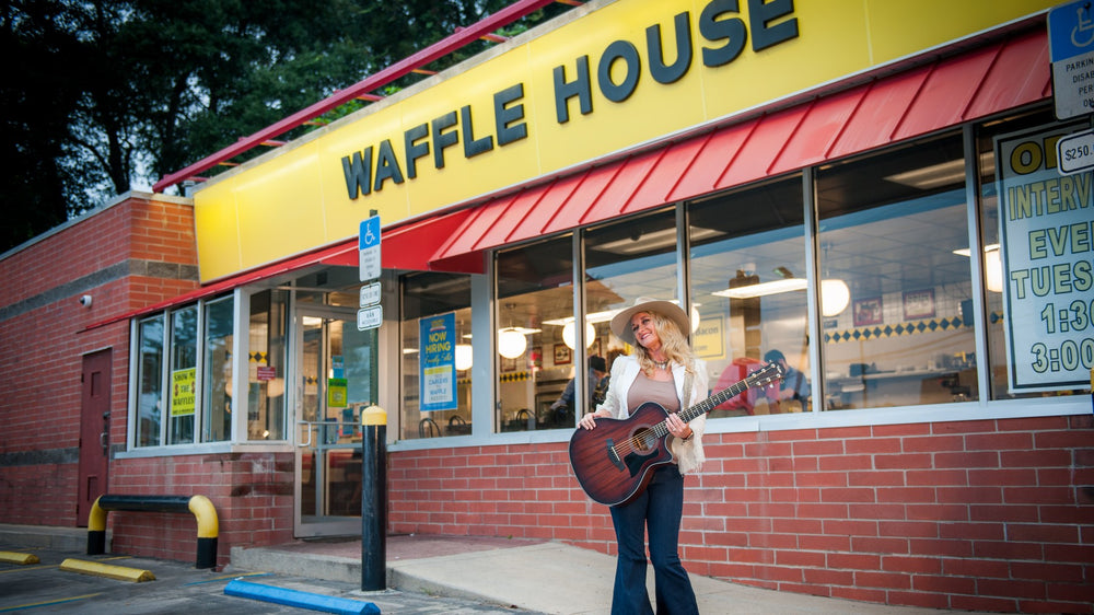 Casey Kearney with her guitar outside a Waffle House at dusk