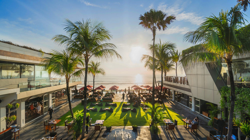 Sunset over the beachfront lawn and palms at KU DE TA in Bali
