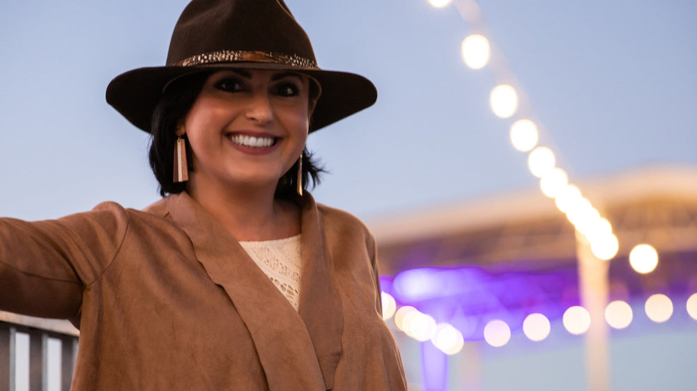 Ragan Smith in a wide-brimmed hat smiling at dusk beside the water