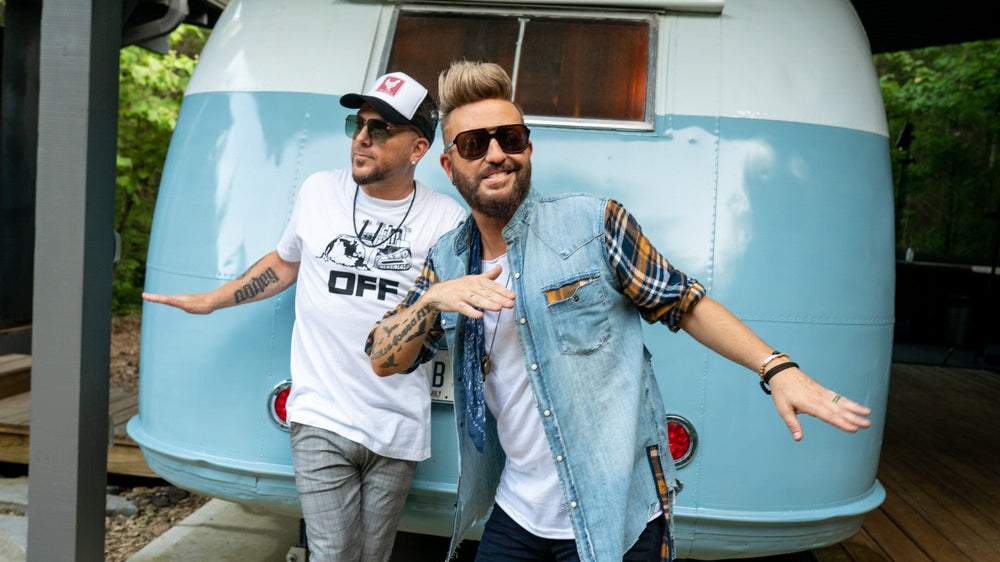 LOCASH posed in front of a vintage aqua camper trailer