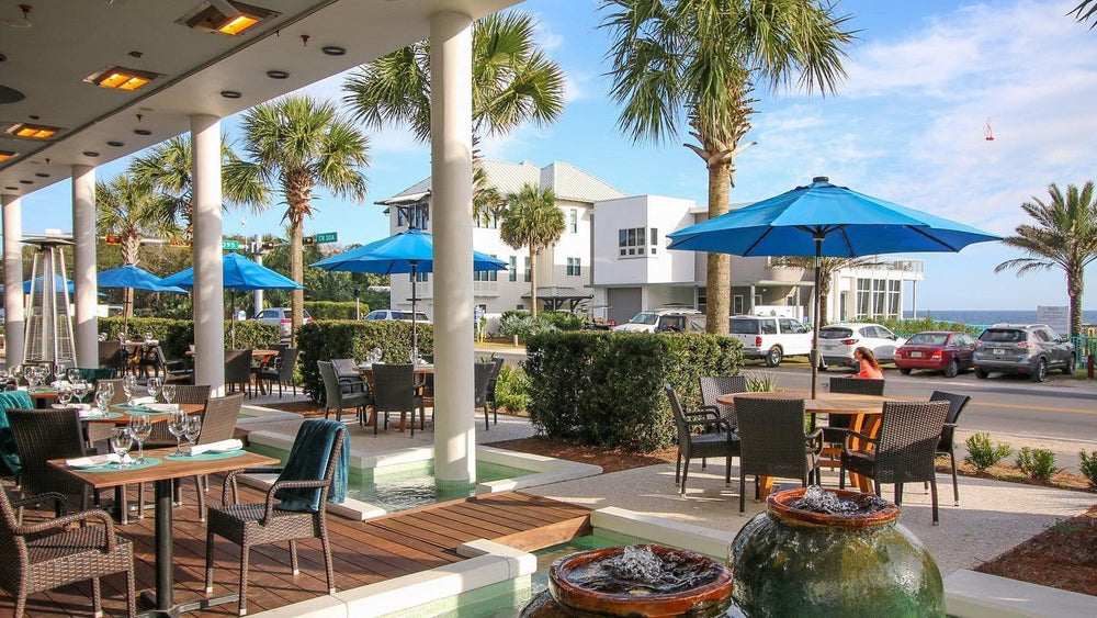 The patio at Surfing Deer on 30A with blue umbrellas and palms
