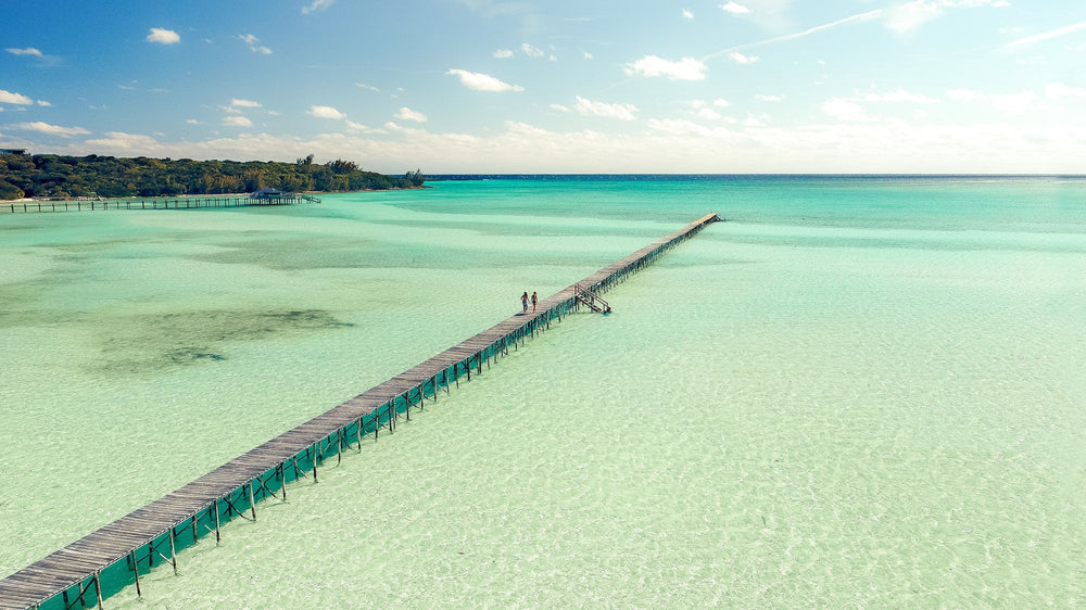 A long wooden dock stretching over the clear turquoise shallows of the Abacos