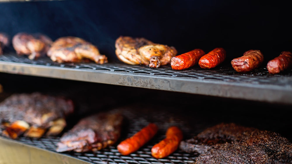 Ribs, chicken and sausages lined up on a hot grill