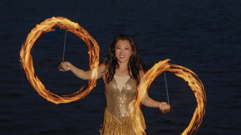 Danielle Torley spinning fire poi at the water's edge